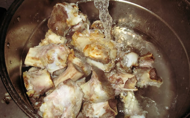 Cho xương heo vào chảo  dầu nóng đảo rồi nêm một ít gia vị vào cho đến khi ngấm